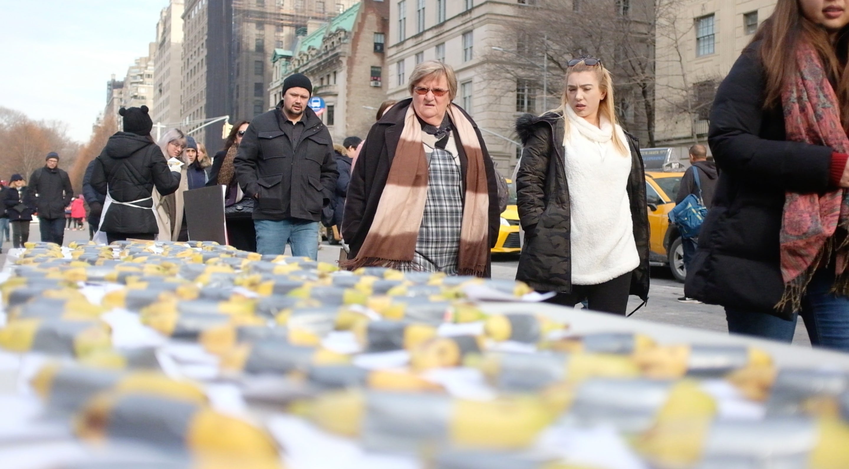 people walking outside the MET and passing a banana art insallation