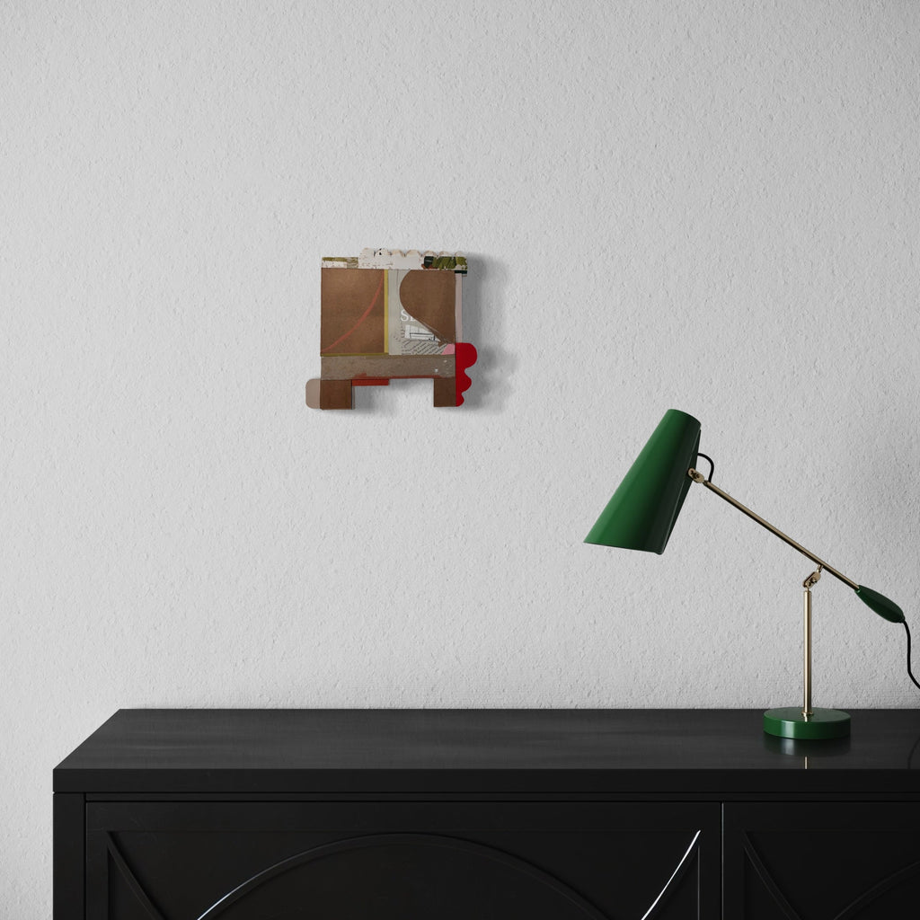 The artwork 'Good Rose' by Janice La Motta features a geometric collage composition with brown kraft paper panels, white scalloped edges, and subtle red accents. Abstract shapes include curved lines, rectangular forms, and printed text fragments. The 9x9.5-inch piece combines textural elements with minimalist design principles.