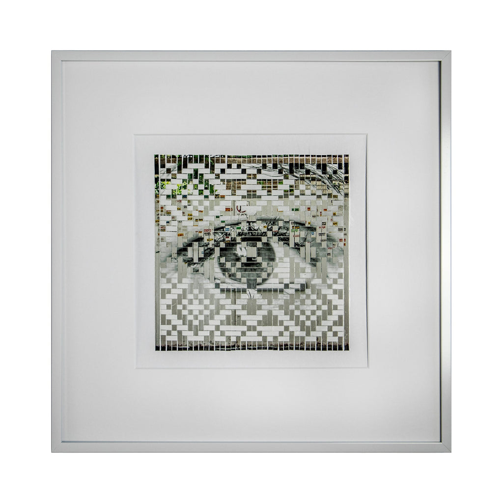 The artwork 'Warning' by Kiana Honarmand features a striking mosaic-style composition depicting an eye created through hand-cut and woven giclee prints. The pixelated pattern combines black, white, and subtle green tones in a geometric arrangement, creating a digital aesthetic within a clean white frame. The eye motif emerges from a checkered pattern with 16x16 inch dimensions.