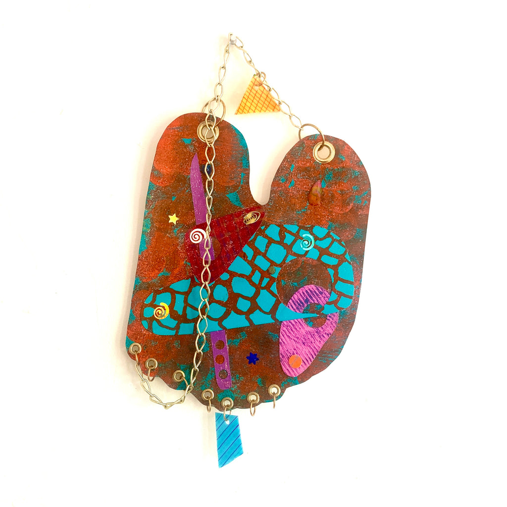 The artwork 'Bunny' features a whimsical abstract design on paper, combining vibrant turquoise mosaic patterns with rust-colored textures. Pink and purple accents create playful shapes, while metallic chain elements and yellow triangular details add dimensional interest. The acrylic painting blends geometric and organic forms in a contemporary style. By Sunny Chapman.