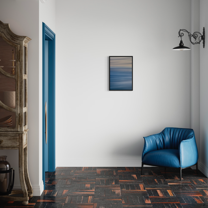 The artwork 'Malibu' by Neil Shapiro features a minimalist interior design scene with a deep blue upholstered armchair against a stark white wall. Above the chair hangs a framed abstract print showing gradient blue and gray horizontal bands. The room includes a vintage-style wall sconce and geometric patterned flooring in terracotta and black tones. By Neil Shapiro.