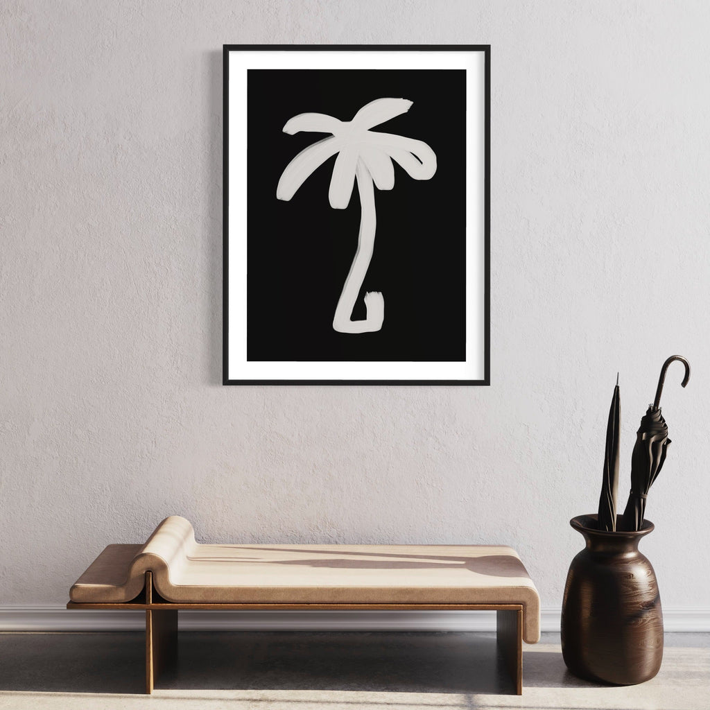 The artwork 'Palm Black And White' by Alina Glotova features a minimalist silhouette of a palm tree in stark white against a deep black background, framed in a modern black frame. The simple, bold design creates a striking contrast, capturing the essence of tropical motif in a contemporary monochromatic style. 40x30 inches print by Alina Glotova.