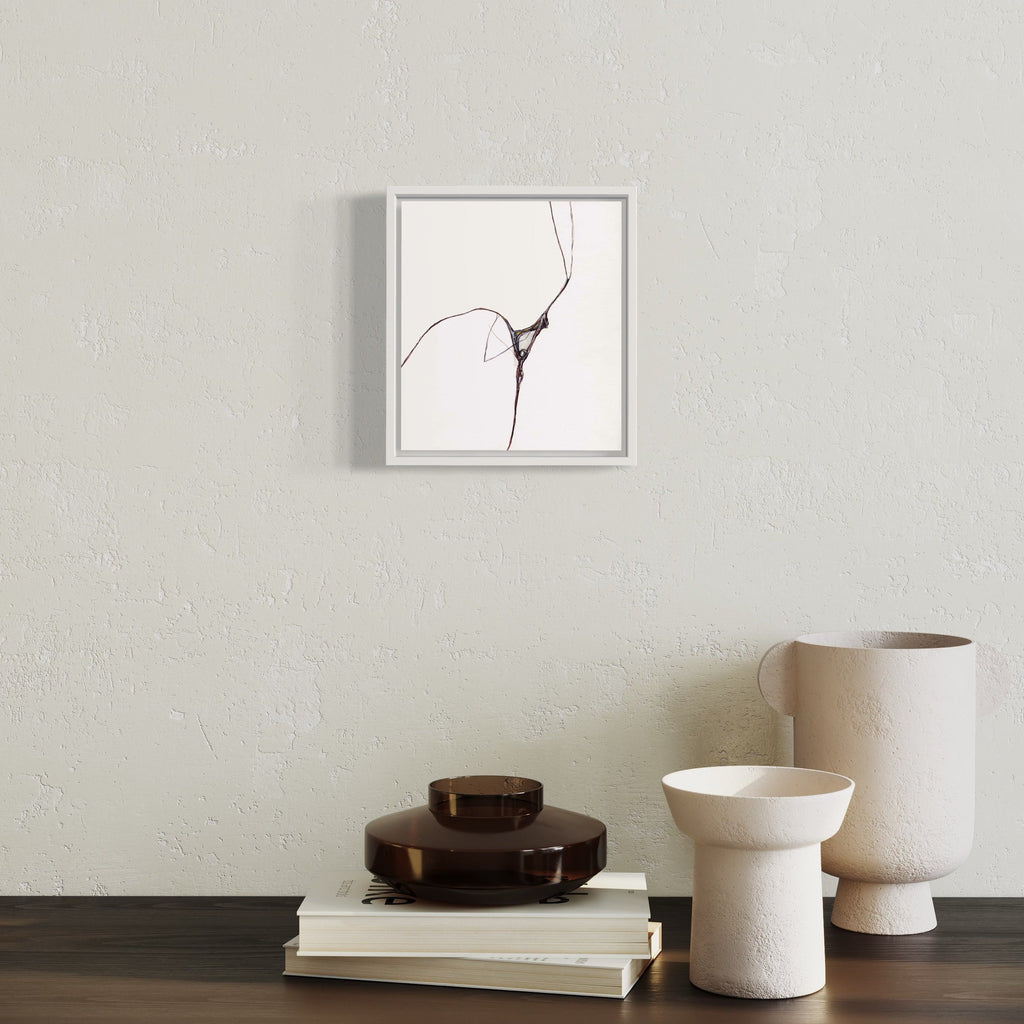 The artwork 'Spider Edge' by Susan Rowe Harrison features a minimalist ink drawing on white paper, depicting delicate intersecting lines creating a subtle crack or web-like pattern. The black lines flow organically against the stark white background, housed in a sleek gray frame, showcasing a contemporary abstract aesthetic. By Susan Rowe Harrison.