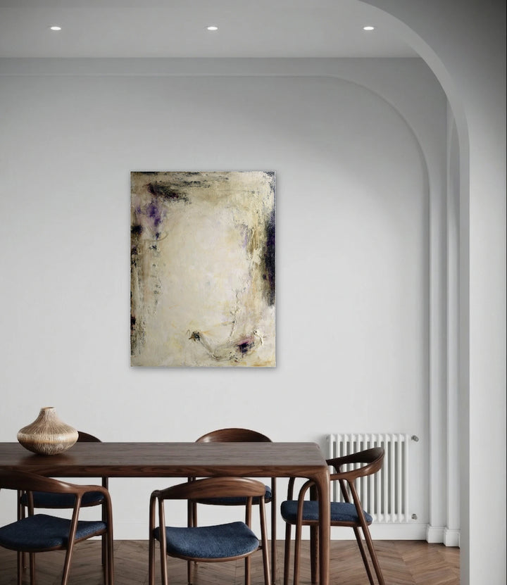 Perseverance by Deb Chaney features a textured abstract artwork with layered neutral tones, subtle hints of purple, and organic forms, displayed in a serene dining space with minimalist decor emphasizing natural light and warm wood furnishings.