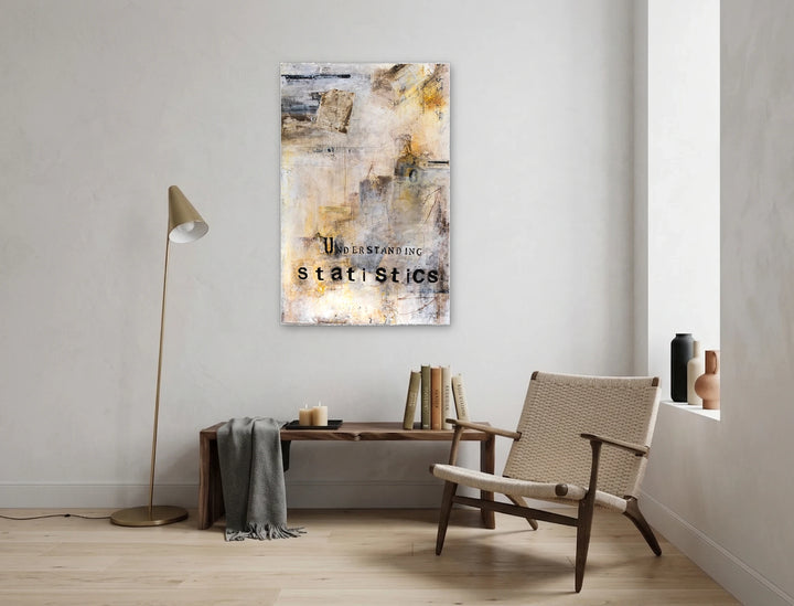 Understanding Statistics by Deb Chaney features an abstract mixed-media composition with layered textures in muted earth tones and pale grays, displayed in a minimalist room with natural light, a wooden bench, woven chair, and simple decor accents.
