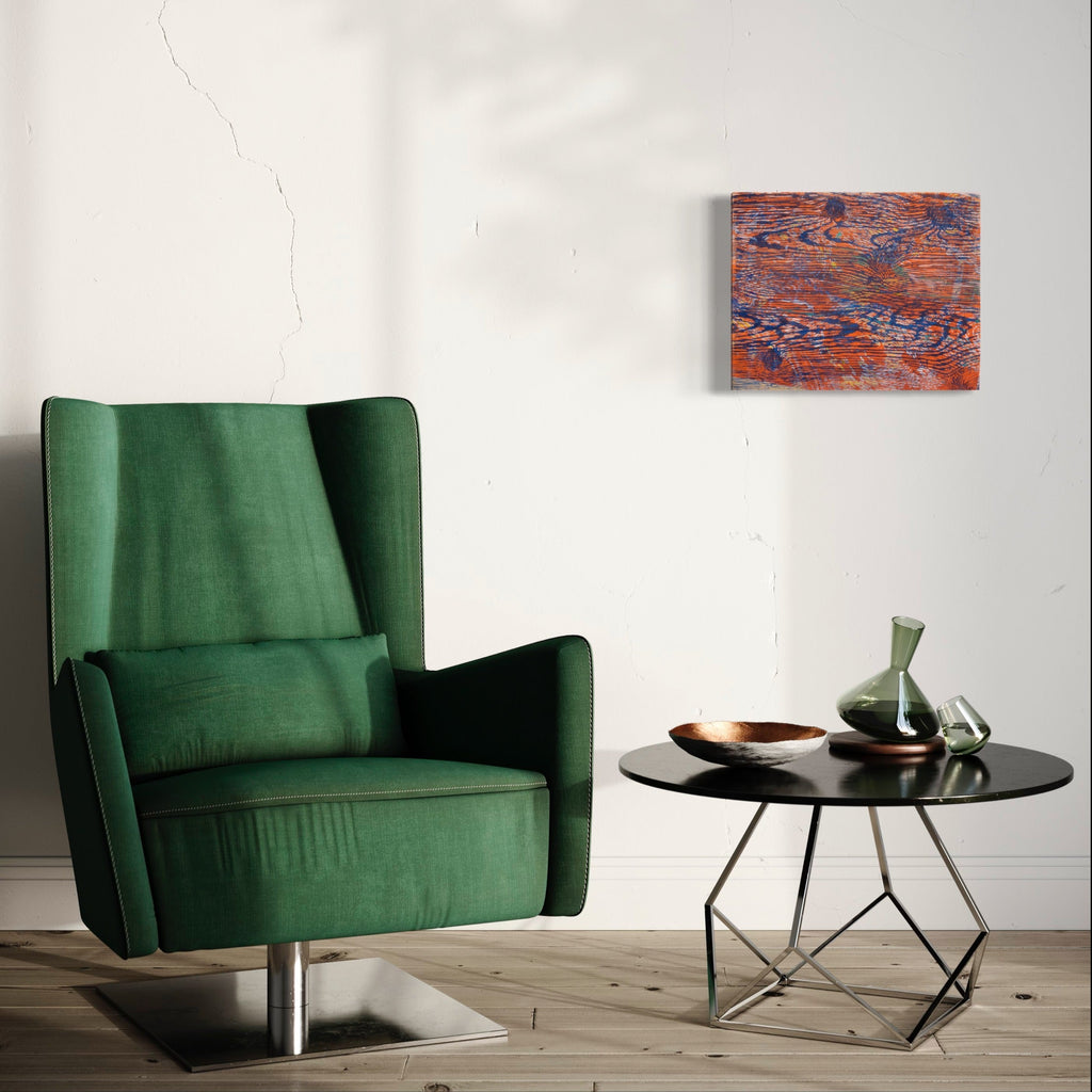 The artwork 'Gutturals' by Emna Zghal features abstract layers of rustic orange and deep blue, creating a weathered, textural effect through woodcut printing and pastel on paper mounted on canvas, displayed above an emerald green armchair and modern black side table in a minimalist interior setting.