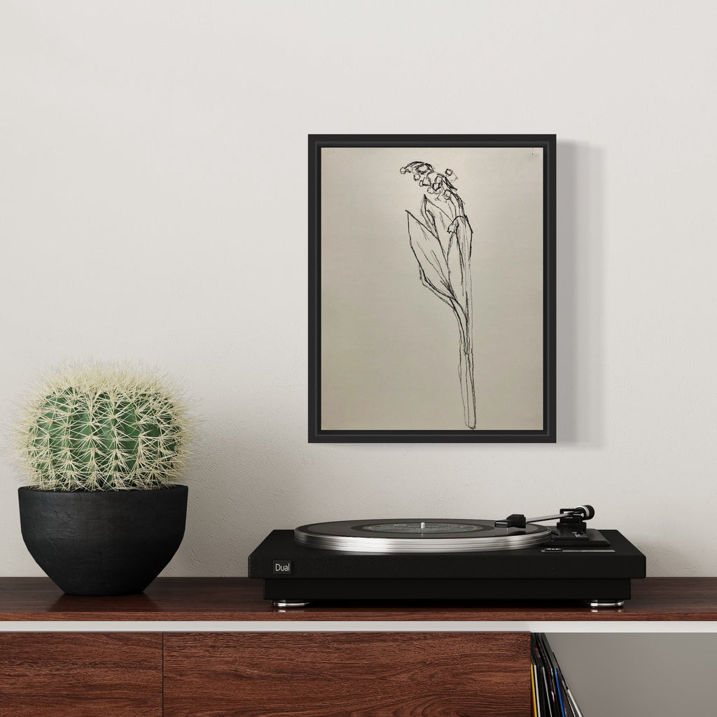 The artwork 'muguet from life, VI' by Ryan Zogheb features a minimalist charcoal sketch of a lily of the valley flower stem on cream-colored paper. The delicate black lines capture the elongated leaves and small bell-shaped blooms with elegant simplicity, displayed in a black frame measuring 14x11 inches. A charcoal drawing by Ryan Zogheb.