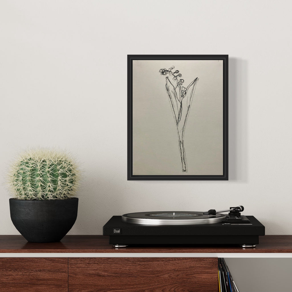 The artwork 'muguet from life, VII' by Ryan Zogheb features a delicate charcoal sketch of a lily of the valley flower, rendered with minimalist lines on light paper. The simple yet elegant drawing captures the plant's distinctive bell-shaped blooms and slender stem, displayed in a black frame alongside a turntable and potted cactus.