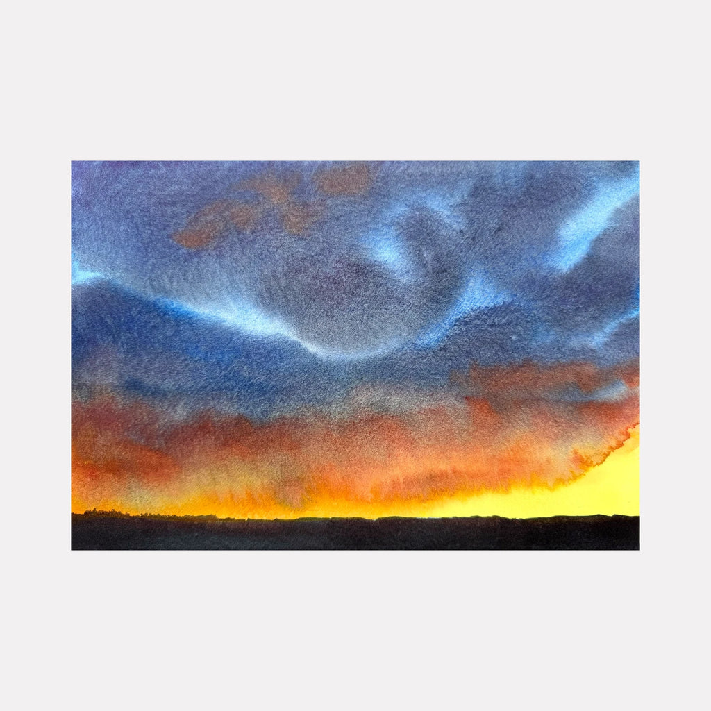Begin Again by Melanie Kozol is a Curina art piece depicting a vibrant sunset where fiery orange and yellow light meets dramatic blue and gray clouds above a dark silhouetted horizon, capturing the transition of day into night through expressive watercolor textures.