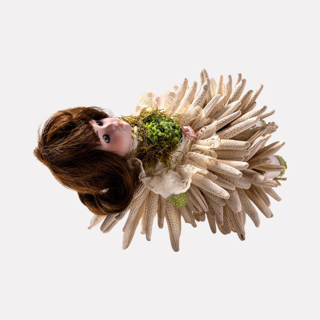Lili Looked Like a Flower by Lisyanet Rodriguez features a handcrafted doll adorned with layered, petal-like fabric elements in neutral tones, accented by a textured green floral bodice, blending delicate natural motifs with artistic craftsmanship for a unique art piece.