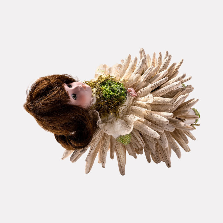 Lili Looked Like a Flower by Lisyanet Rodriguez features a handcrafted doll adorned with layered, petal-like fabric elements in neutral tones, accented by a textured green floral bodice, blending delicate natural motifs with artistic craftsmanship for a unique art piece.