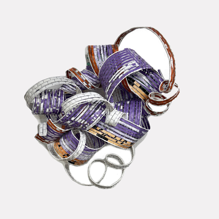 Ouroboros by Shelley Heffler is a Curina art piece featuring an intricate metallic sculpture composed of interwoven bands in purple, silver, and copper tones, creating a dynamic, textured form with a sense of fluidity and continuous motion.
