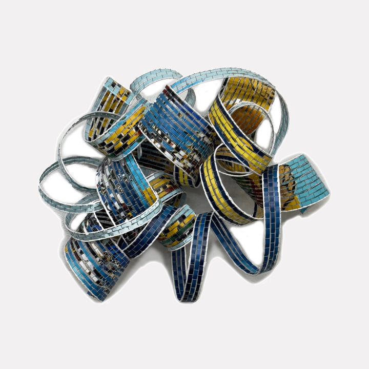 Out of this World by Shelley Heffler is a Curina art piece featuring an intricate, looping abstract form with mosaic-like patterns in shades of blue, yellow, and black, creating a dynamic and textured sculptural composition that evokes movement and celestial inspiration.