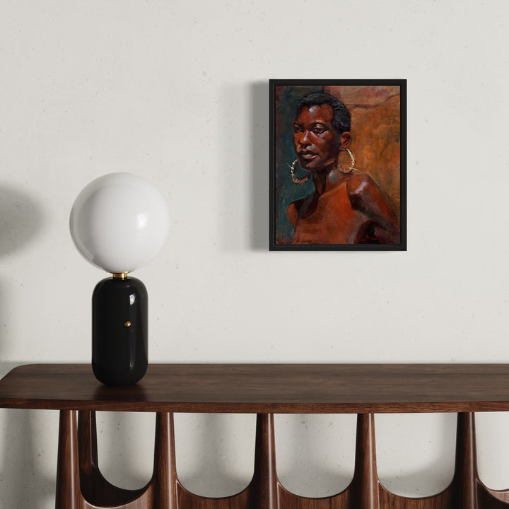 The artwork 'Tatania' by JaeMe Bereal features a striking portrait against a warm terracotta background. The high-quality lithograph on canvas showcases expressive brushwork, rich earth tones, and dramatic lighting. The composition includes a circular white lamp with black base on a wooden console table, creating elegant contrast with the framed artwork measuring 20x16 inches.