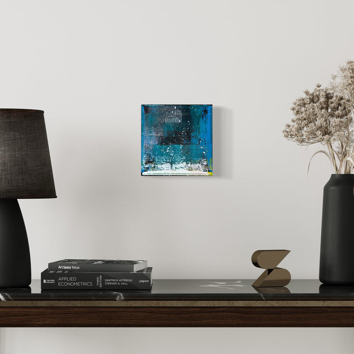 The artwork 'Voyage 5' by Bill Burns features a striking abstract composition in vibrant turquoise and deep navy blues, with textural elements creating a dramatic waterfall effect. The acrylic painting on 8x8 canvas showcases dynamic brushstrokes and layered paint applications, suggesting movement and depth through contrasting light and dark values.