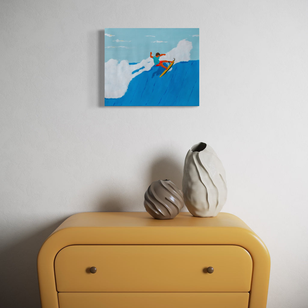 Agua Snaps by Alimo features a vibrant surfer in orange on a yellow board soaring above a bright blue wave, set against a soft sky with white clouds, displayed above a modern yellow dresser with two textured ceramic vases, offering lively coastal art in a minimalist space.