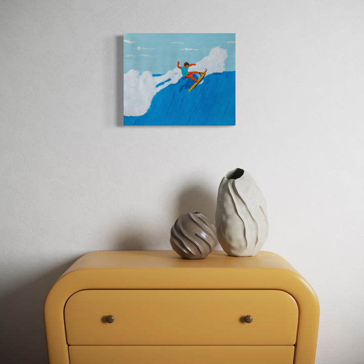 Agua Snaps by Alimo features a vibrant surfer in orange on a yellow board soaring above a bright blue wave, set against a soft sky with white clouds, displayed above a modern yellow dresser with two textured ceramic vases, offering lively coastal art in a minimalist space.