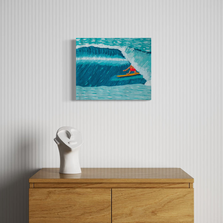Tropic Shelter by Alimo features a lone surfer in bright orange on a yellow board navigating a large curling wave, rendered in rich blue and teal tones that capture energetic ocean motion within a minimalist interior setting.