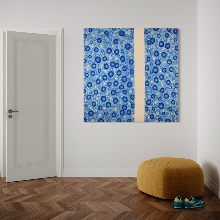 The artwork 'Implicate Order' by Eric Jiaju Lee features a mesmerizing pattern of circular forms in varying shades of blue, separated by a vertical cream-colored band. The organic, bubble-like shapes create a rhythmic composition across the canvas, reminiscent of cellular structures or water droplets. The 60x60 inch acrylic painting combines abstract expressionism with geometric precision.