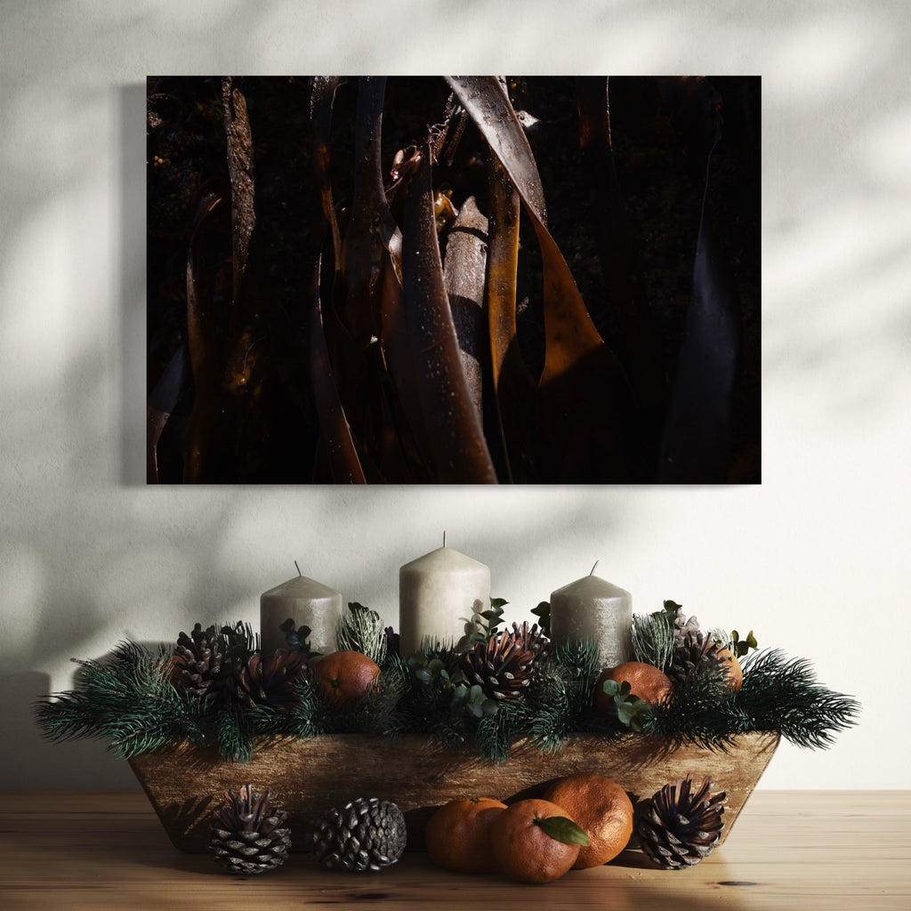 080A5884 by Eunice Pais showcases dark, flowing organic shapes with rich textures and subtle highlights. Mounted above a wooden surface adorned with natural pinecones, candles, and citrus fruits, the artwork adds a deep, contemplative atmosphere to the warm, nature-inspired interior setting.