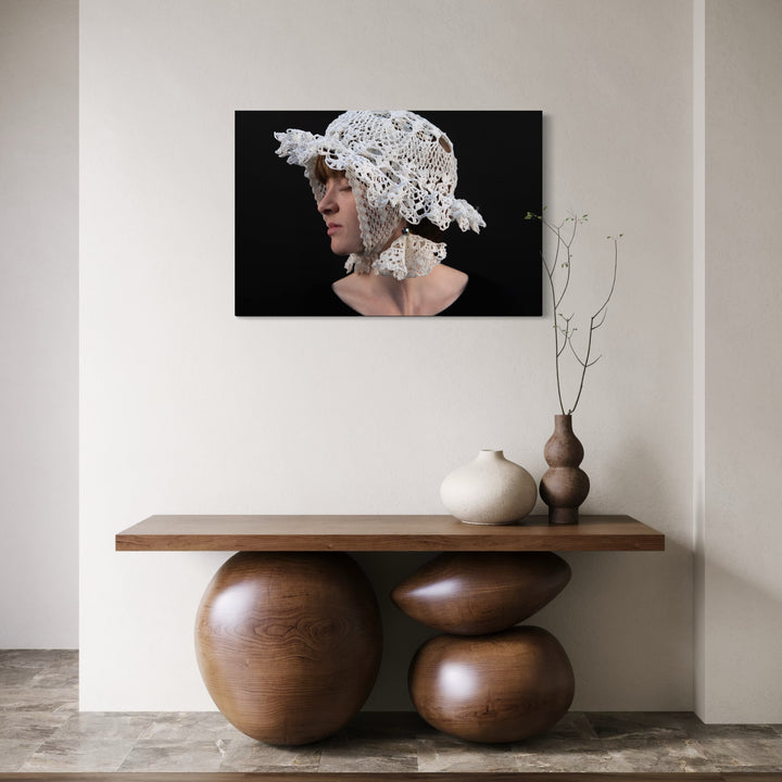 080A8649 by Eunice Pais presents a profile of a person wearing an intricate white lace bonnet against a black backdrop, capturing a delicate interplay of texture and light. Displayed above a sculptural wooden console with minimalist vases, the artwork brings an elegant, contemplative atmosphere to the serene, modern space.