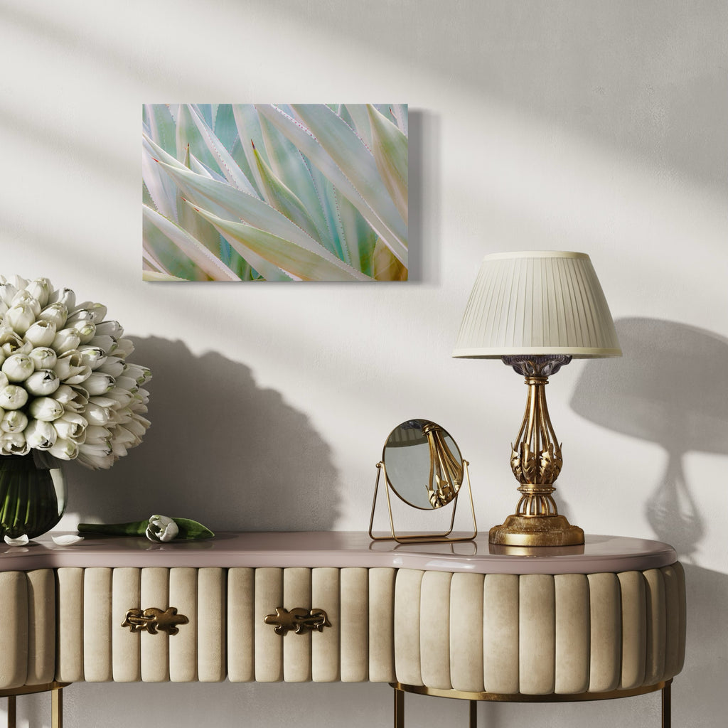 The artwork 'Agave Party' by Neil Shapiro features a close-up view of agave plant leaves in soft, ethereal tones. Sharp, angular succulent leaves in pale mint green and ivory create a layered, geometric pattern. The textured Hahnemühle print captures delicate water droplets and natural highlights along the serrated edges, producing a dreamy, botanical abstract composition.