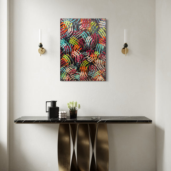 Cosmic Dance by Hillary Hany features a vibrant, abstract composition of overlapping, multicolored curved lines creating a dynamic, rhythmic pattern. Displayed against a neutral wall over a sleek black marble console table with sculptural brass legs, flanked by minimalist wall sconces, it brings energetic movement and modern elegance to the space.