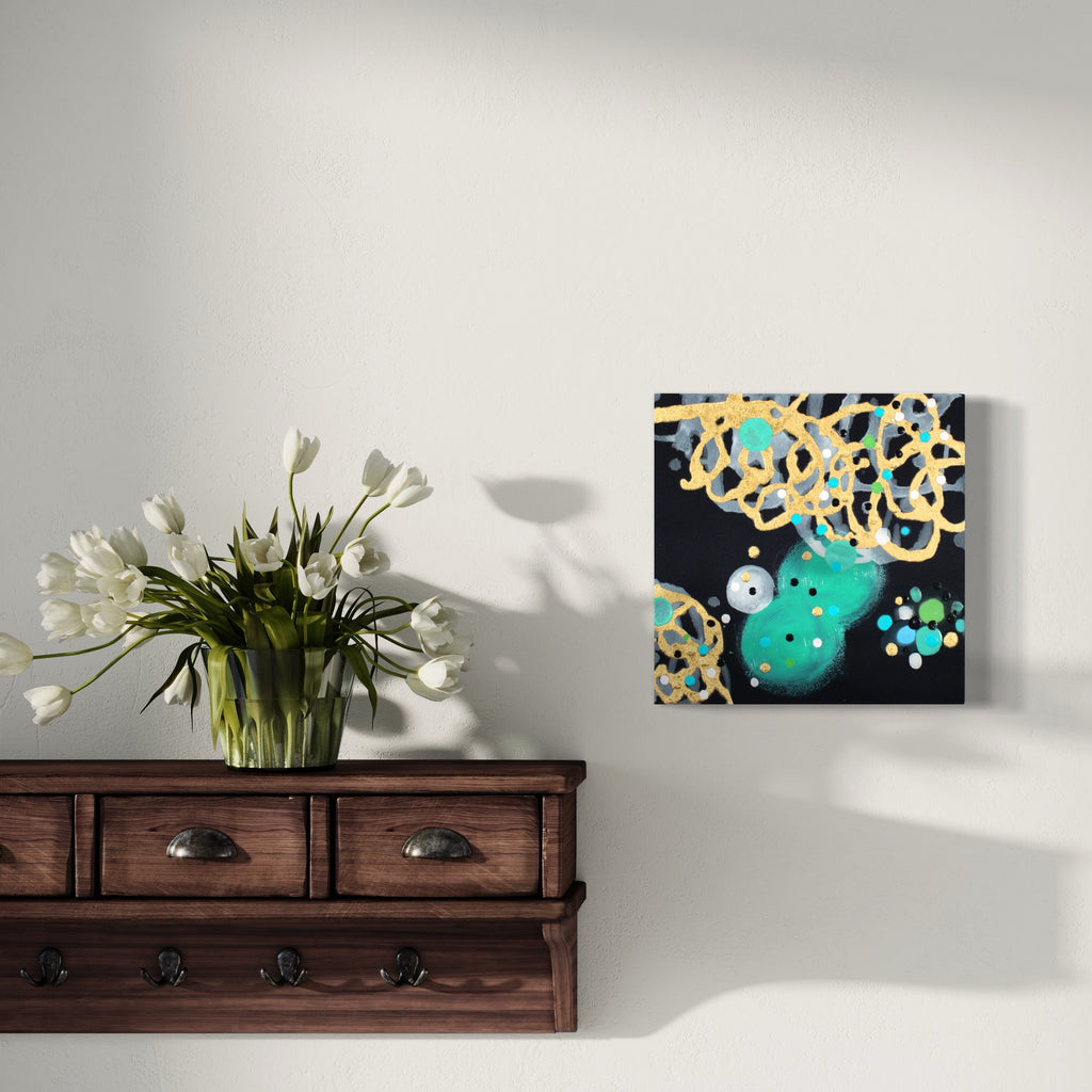 The artwork 'Darling Derring-Do' by Eric Jiaju Lee features abstract swirling patterns in golden yellow intertwining with a vibrant turquoise circular form against a deep black background. The acrylic on silk painting showcases delicate brushwork with small blue floral accents, creating a dynamic and whimsical composition measuring 12 x 12 inches.