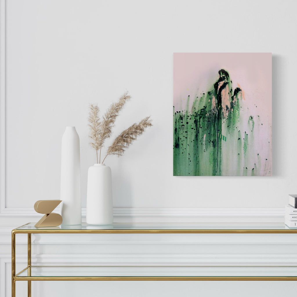 The artwork 'GreenMossSlide' by Devin Ruiz features dramatic vertical brushstrokes in emerald green cascading down a soft pink background, creating an ethereal waterfall effect. Abstract fluid acrylic technique on canvas shows organic dripping patterns and textural details, measuring 16x20 inches. Dark green accents add depth while misty white undertones create atmospheric dimension.