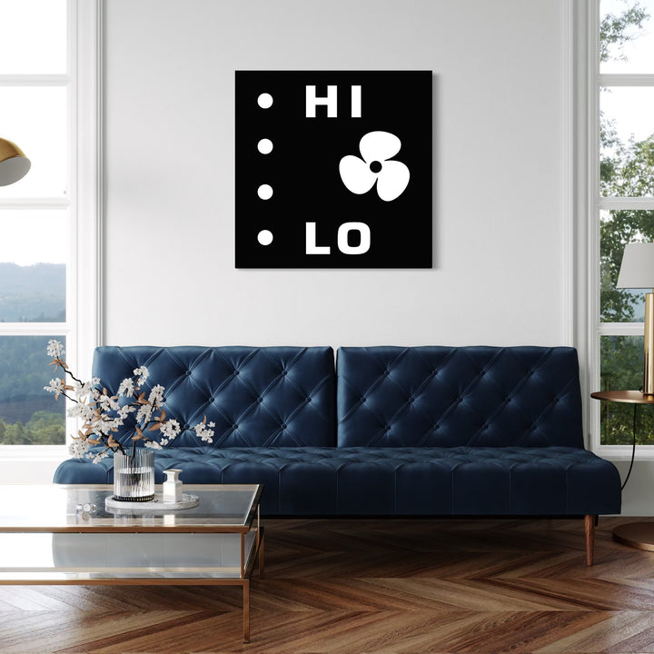 HI LO by Harold Herb displays bold white text and abstract shapes on a black square canvas. The artwork is mounted on a clean white wall above a deep blue tufted sofa in a bright, contemporary living room with large windows and a glass coffee table adorned with a simple floral arrangement.