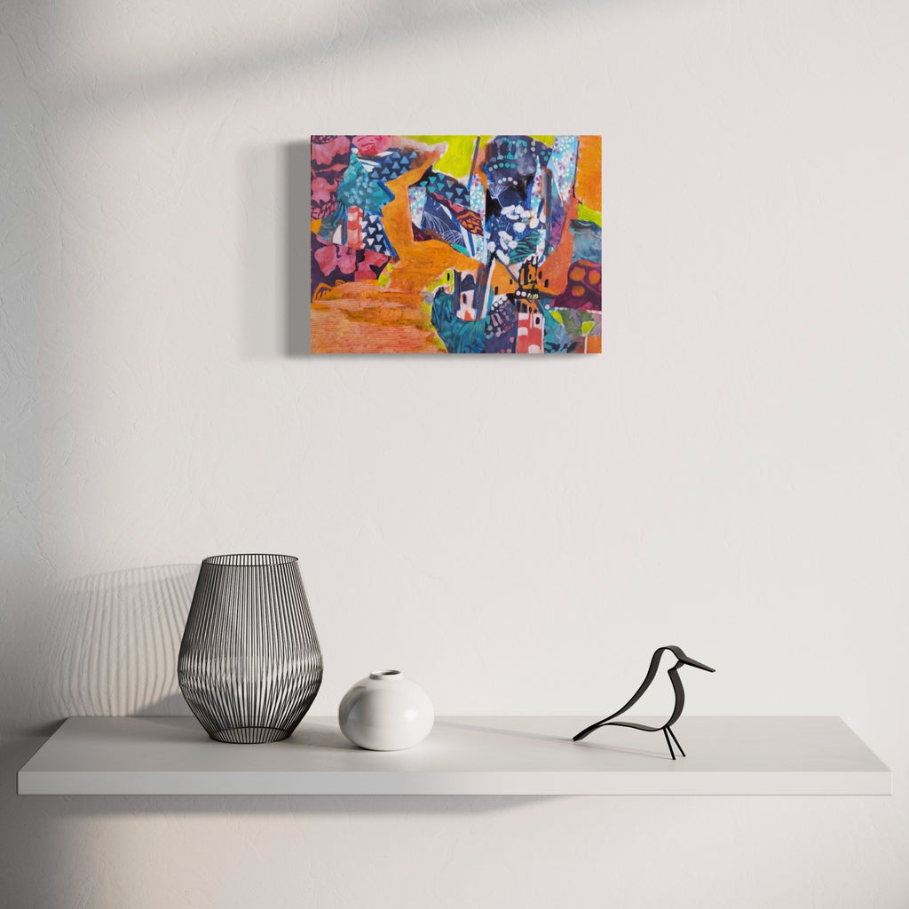 The artwork 'Hilltop Village' by James Ehling features a vibrant abstract landscape rendered in acrylic and fabric collage. Small geometric houses nestle among patterned shapes in deep blues, pinks, and turquoise against a warm orange sky. Textural elements and whimsical architectural forms create a playful, mixed-media composition on canvas that measures 16 by 12 inches. Artwork by James Ehling.