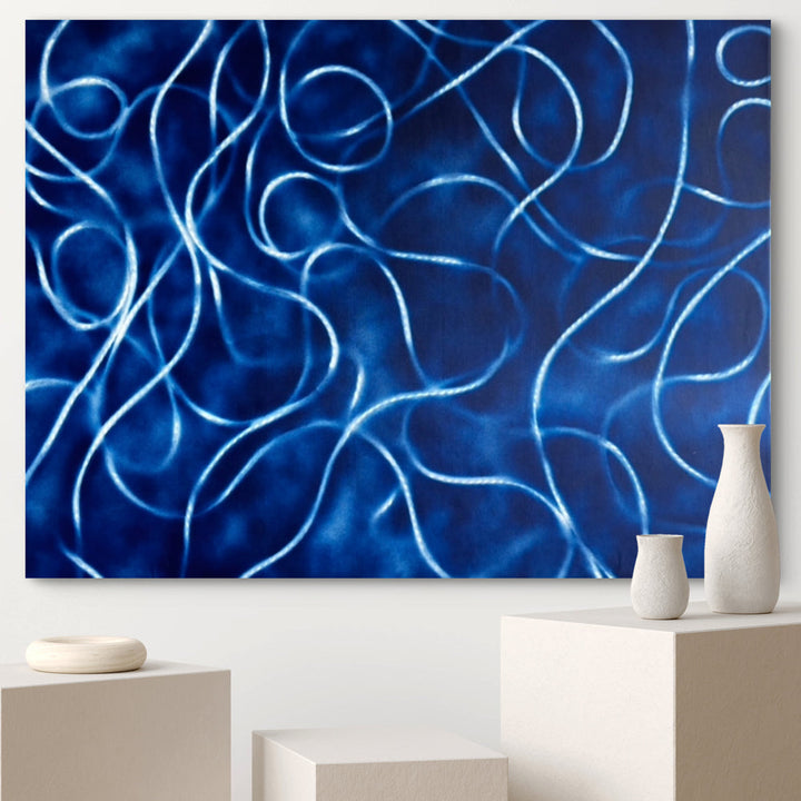 The artwork 'La Danse' by Gina Iannucci features mesmerizing swirling lines in luminous electric blue against a deep navy background. The spray paint technique creates fluid, ribbon-like curves that interweave across the canvas, suggesting graceful movement and rhythm. The contemporary abstract composition measures 36x48 inches and showcases a dynamic interplay of light and shadow.