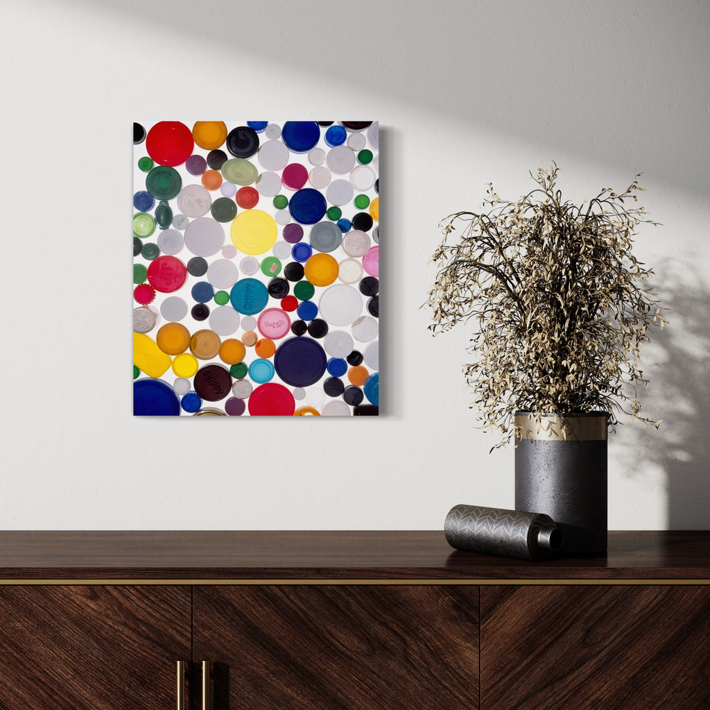 The artwork 'MDC' by Dirk Westphal features vibrant circular plastic bottle caps arranged in a dynamic pattern. Multicolored caps in red, blue, yellow, green, and white create an abstract composition against a light background. Various sizes of caps create depth and visual rhythm in this 24x20 inch signed photographic print.