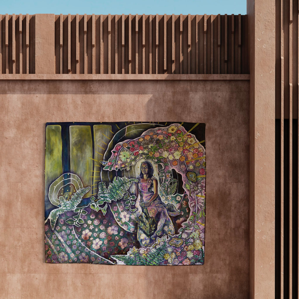 The artwork 'My Trees Were Once Bare But Are Now Full of Flowers' depicts a whimsical garden scene with vibrant floral patterns, swirling botanical motifs in pink, yellow, and green hues. A figure sits amidst lush foliage and blooming flowers, surrounded by intricate screen-printed details and hand-sewn elements on muslin canvas. Artwork by Laurie Shapiro.