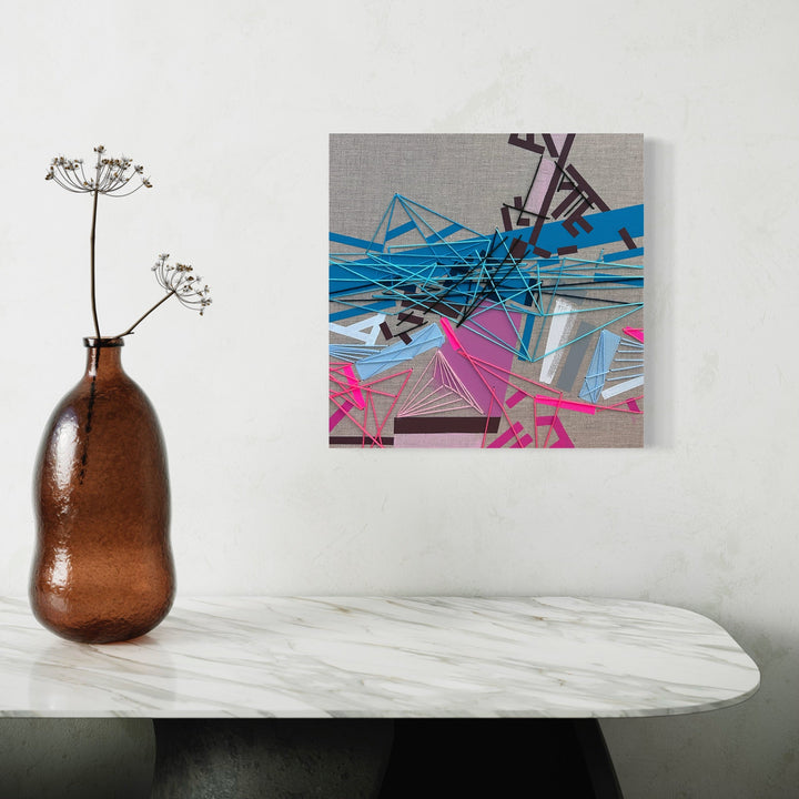 The artwork 'Ojjaaas' by Philippe Halaburda features dynamic geometric abstractions with intersecting blue and pink lines creating an angular composition. The piece combines acrylic paint with textural elements of tape and yarn on canvas, displaying sharp edges and overlapping shapes against a grey background. 20x20 inches abstract modern artwork by Philippe Halaburda.