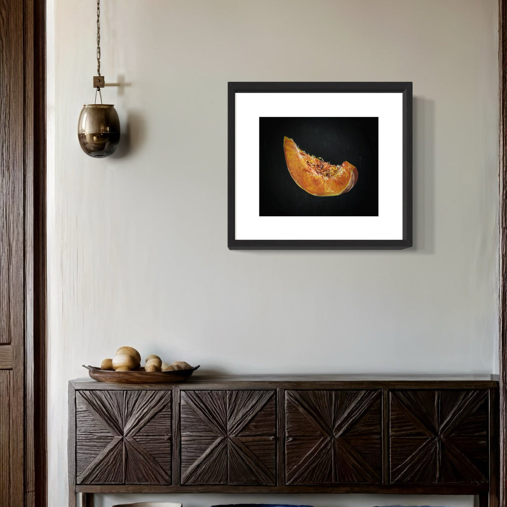 The artwork 'PUMPKIN SL(P)ICE & ALL THINGS NICE' by Shweta Matai captures a vibrant orange pumpkin slice against a dramatic black background. The oil painting showcases intricate details of pumpkin flesh and seeds, creating a striking contrast with rich textures and realistic shadows, displayed in a black frame with white matting.