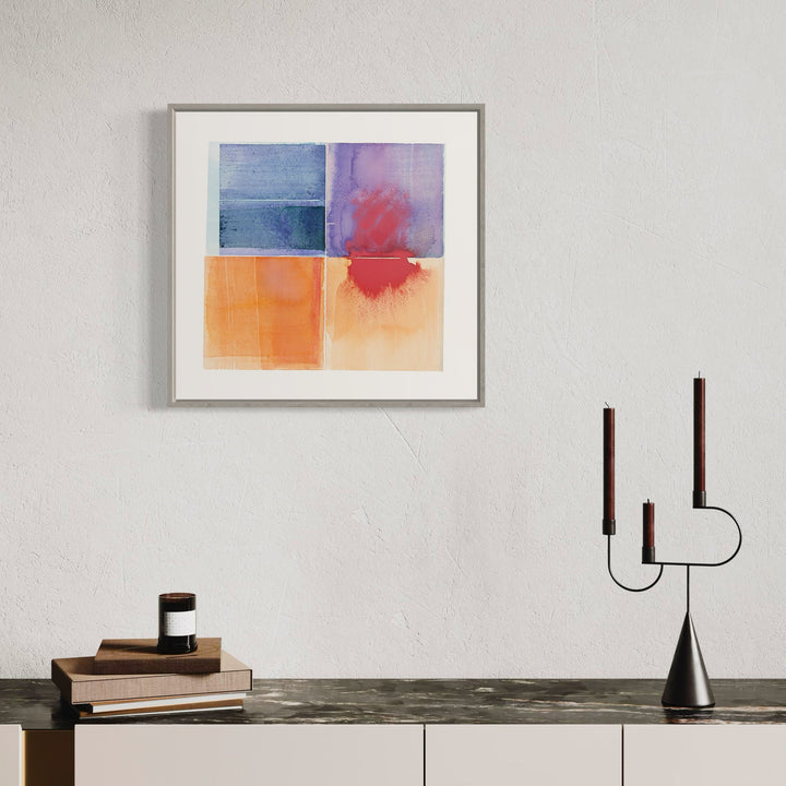 The artwork 'Penumbra' by Ken Schiano features a quadriptych watercolor composition with distinct color blocks. Upper panels showcase deep blue and purple-red hues, while lower panels transition through warm orange and peach tones. The abstract squares display subtle color bleeds and watercolor textures, framed in a minimalist gray frame, measuring 21x22 inches.