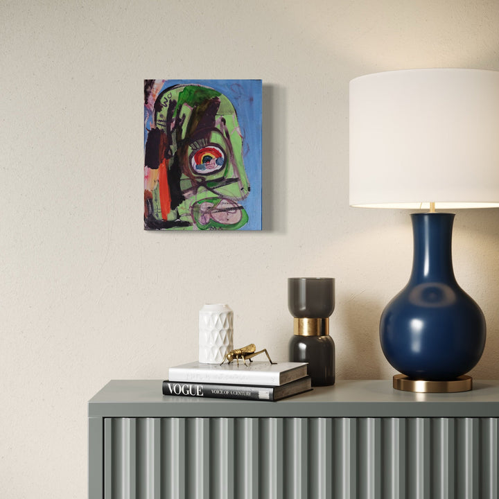The artwork 'Pia Posse Mask' by Devin Ruiz features an abstract expressionist portrait rendered in vibrant green, black, and red against a blue background. The acrylic painting on canvas showcases bold brushstrokes creating a dynamic mask-like form with distinctive circular elements resembling eyes, executed in an energetic contemporary style by Devin Ruiz.