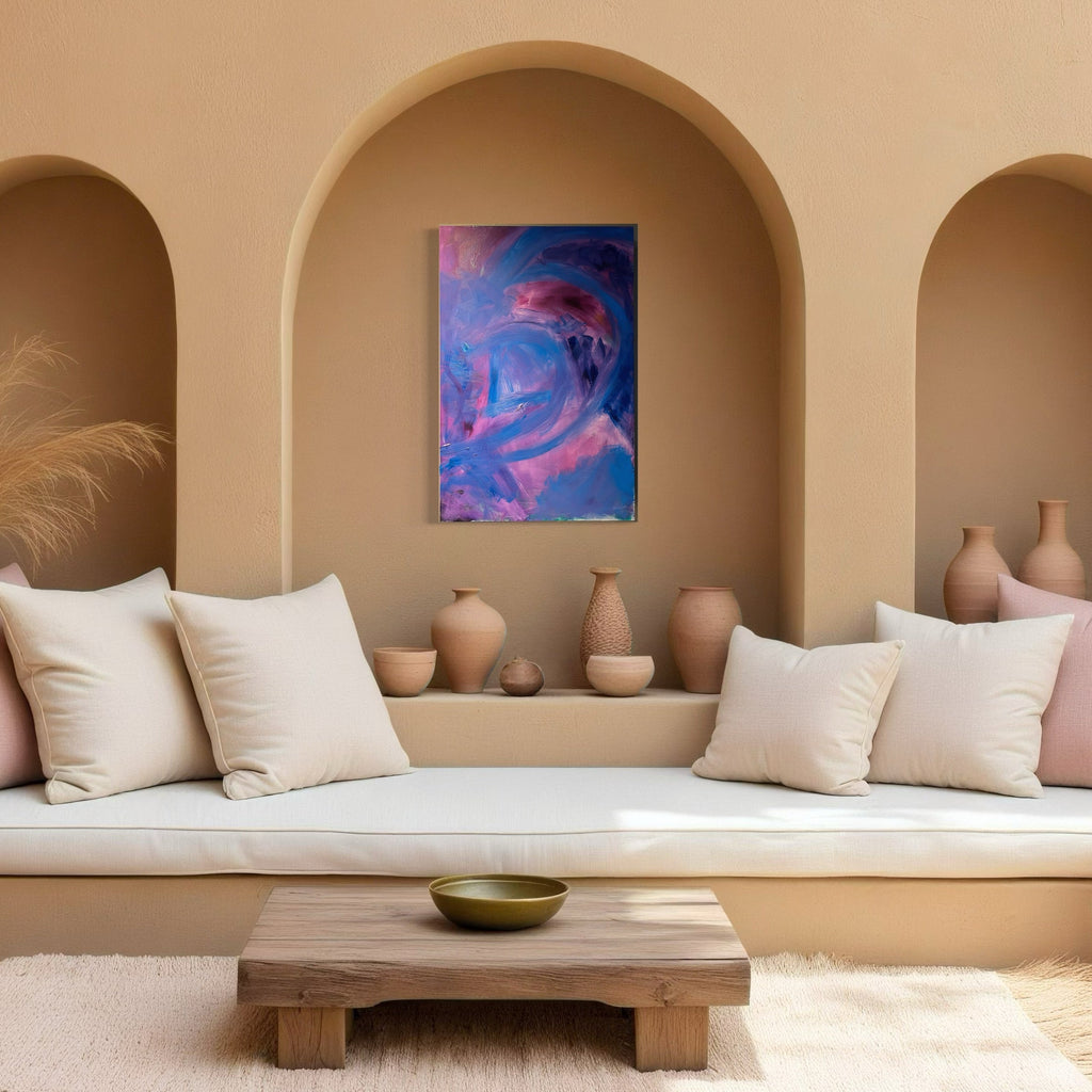 The artwork 'Possibilities Too' by Genevieve Antonello features swirling abstract forms in vibrant purple and blue hues with touches of pink, displayed in a Mediterranean-style alcove with terracotta walls. The oil on board painting creates a dynamic, fluid movement against neutral ceramics and white cushions, measuring 36x24 inches.