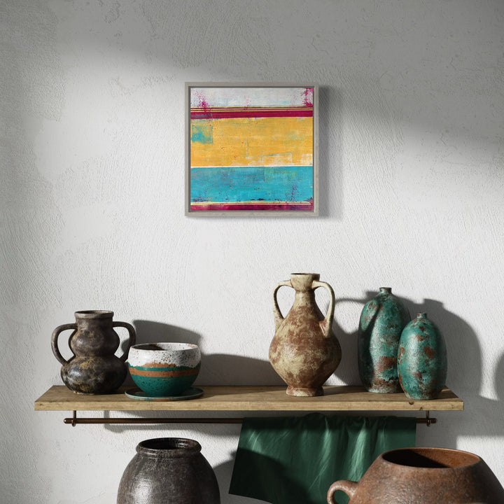 The artwork 'Raw Days' by Karen L. Burns features horizontal color blocks in vibrant red, golden yellow, and turquoise blue, created with acrylic and mixed media. The abstract composition showcases textured brushstrokes and weathered effects, suggesting a raw, natural aesthetic. The 12x12 inch piece evokes a modern coastal or desert landscape with its bold, distressed layering and contemporary color palette.