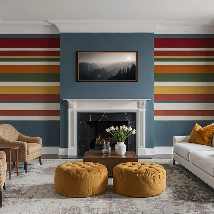 Remanoir by Kyle Murphy showcases a peaceful black and white mountain scene with soft sunlight filtering through mist, highlighting the silhouettes of tall trees. The artwork provides a quiet focus above a white fireplace in a warm, modern living room accented by mustard yellow and deep blue tones.