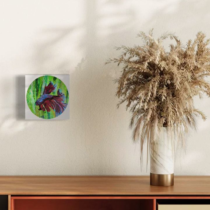 The artwork 'Rendevous with Rama' by Natasha Papousek features a vibrant circular collage depicting a purple and blue betta fish swimming against a bright green background. The painted paper collage mounted on an 8-inch round wooden panel showcases dynamic movement through layered textures and bold color contrasts, creating an ethereal underwater effect.