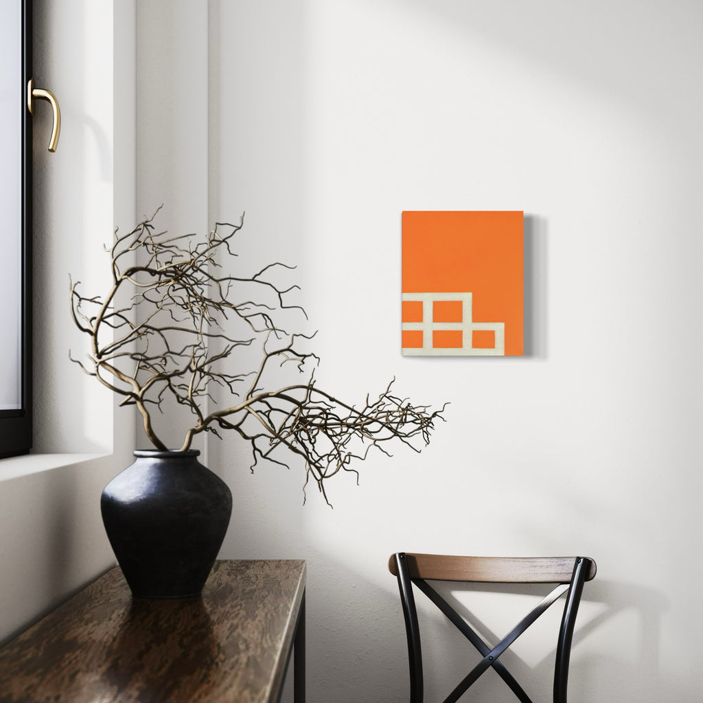 The artwork 'Roots' by Shyun Song features abstract geometric squares in vibrant orange on canvas, displayed in minimalist interior setting