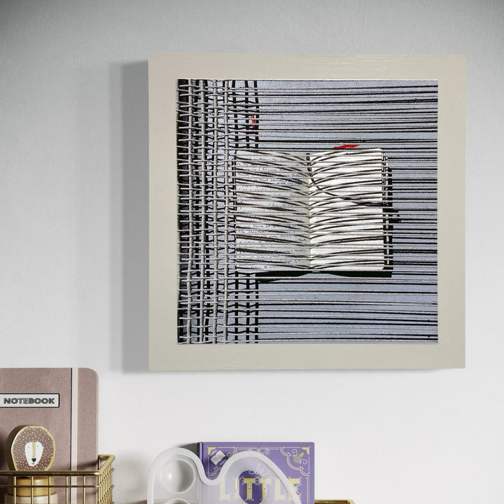 The artwork 'Sentence Structure String 3' by Anne Sherwood Pundyk features a minimalist composition of parallel horizontal black lines forming a geometric pattern, with a central book-like shape emerging in white. A subtle touch of red accent breaks the monochromatic scheme. The piece is mounted on a white panel, creating a striking visual rhythm with its linear pattern.