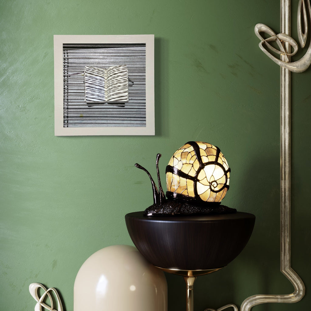 Sentence Structure String 4 by Anne Sherwood Pundyk features a minimalist white book-like form against horizontal black lines, mounted in a square white frame. The artwork is displayed on a sage green wall, creating striking visual contrast. Archival inkjet print on wood panel with latex paint, expressing geometric abstraction and textural depth.
