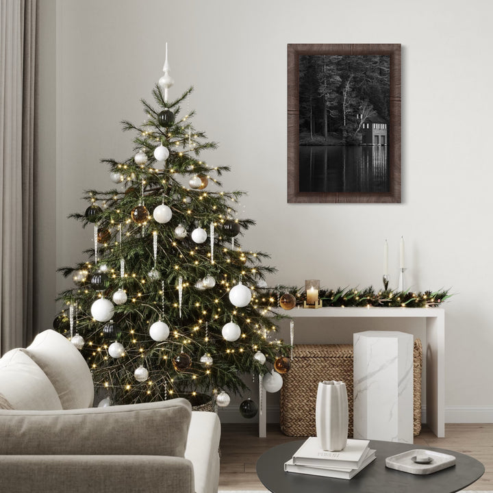 Shadows Rest by Kyle Murphy captures a quiet lakeside scene in black and white, featuring a rustic boathouse nestled among tall trees. The still water reflects the structure and surrounding forest, evoking a peaceful, meditative ambiance within a natural woodland landscape.