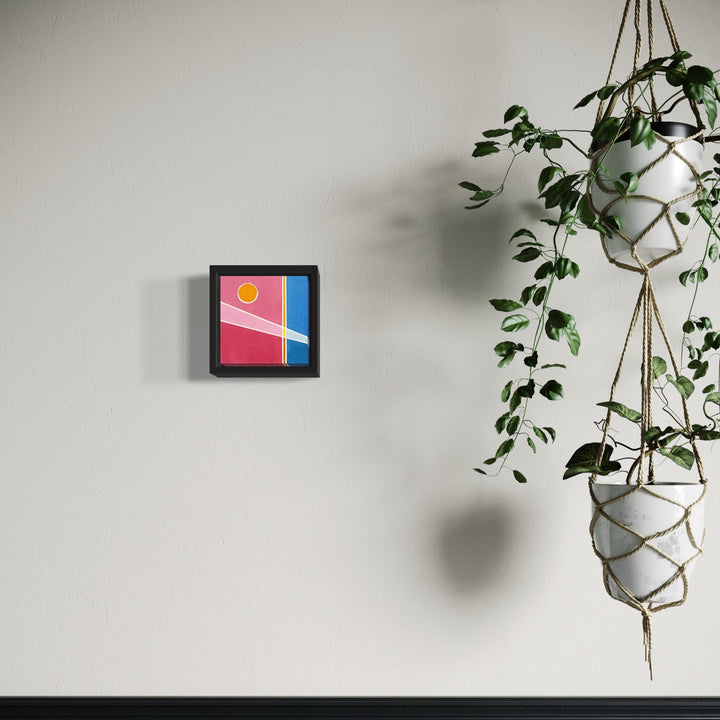The artwork 'Sol' by Arthur Norcome features a minimalist geometric composition in watercolor, displaying a vibrant yellow sun circle against a pink and blue divided background. The 5x5 inch piece is framed in black, creating a striking contrast with its abstract modernist design and warm-cool color interplay.