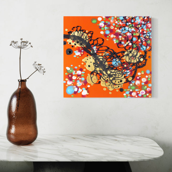 The artwork 'Spilling Upwards Over Blossoms' by Eric Jiaju Lee features a vibrant orange background adorned with abstract black and gold swirling forms, surrounded by scattered multicolored dots resembling cherry blossoms. The acrylic on silk painting combines fluid organic patterns with delicate floral elements in blue, white, and red tones. - Eric Jiaju Lee
