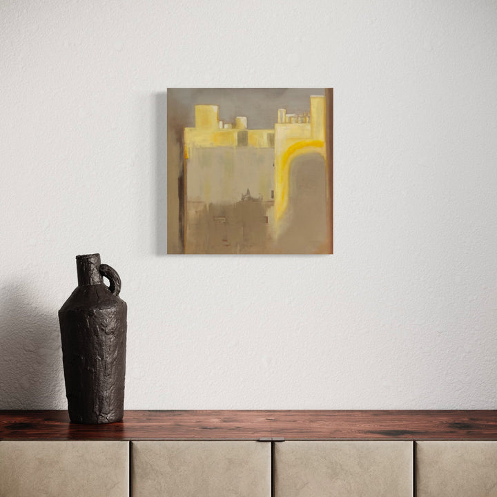 The artwork 'Sunset in the East-3' by Cora Jane Glasser features abstract geometric forms in luminous yellow and muted taupe tones, creating an architectural cityscape impression on stretched linen. A curved yellow arc suggests sunlight, while blocky shapes evoke urban buildings bathed in evening light. Oil painting technique creates subtle textural variations across the 20x20 inch canvas.