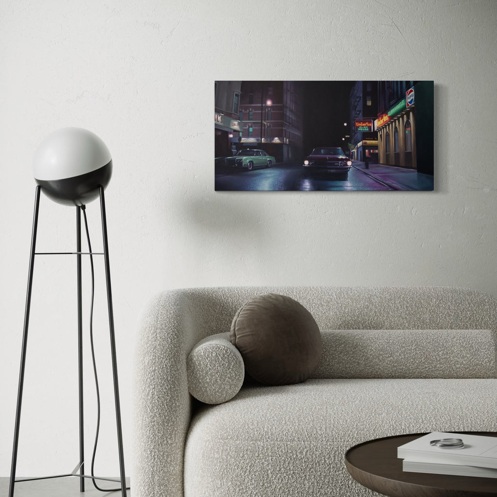 The artwork 'The Irishman' by Alex Devereux captures a moody urban nightscape featuring vintage automobiles parked along a dimly lit street. Neon signs glow against dark buildings, creating atmospheric contrast in deep blues and muted colors. The 15x30 inch acrylic painting on canvas evokes a noir aesthetic with its masterful use of light and shadow in the cityscape setting.